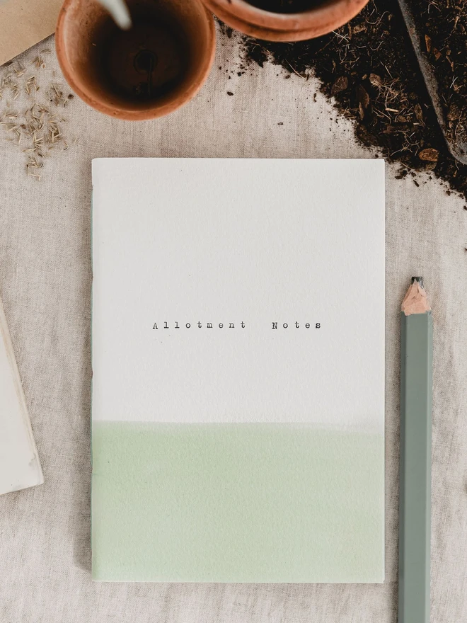 soft green and white gardening journal with the text 'allotment notes' typed on the cover