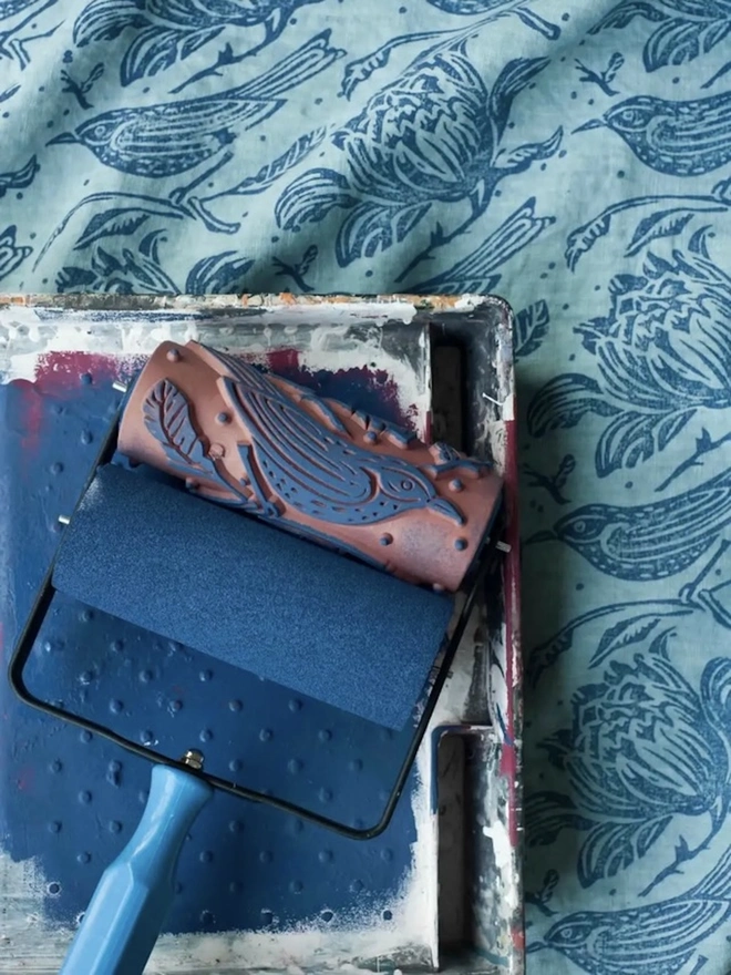 Flock Patterned Paint Roller, with blue paint in tray. 