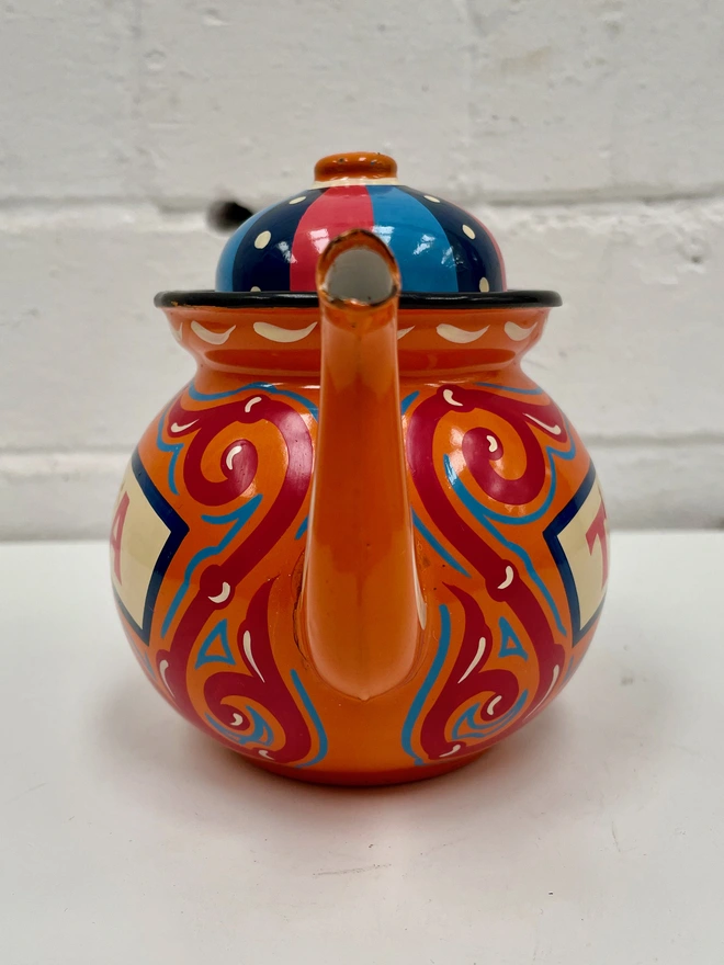 Small orange vintage teapot, hand painted with a design inspired by traditional scrollwork.