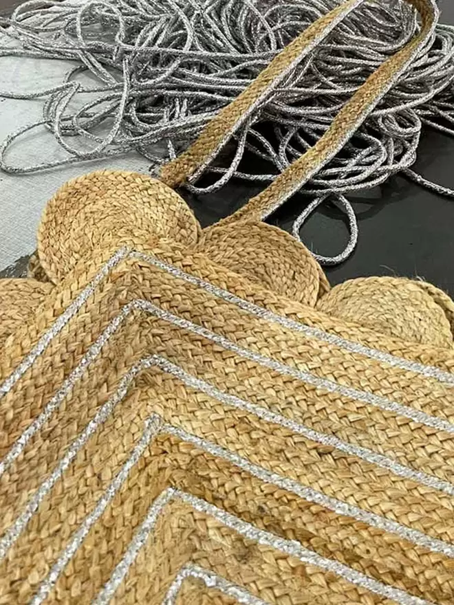 Close up of silver braiding detail woven into jute mat with scalloped edging