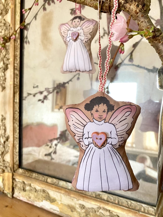 lavender fairy bag hung on a pink blossom branch in front of a mirror