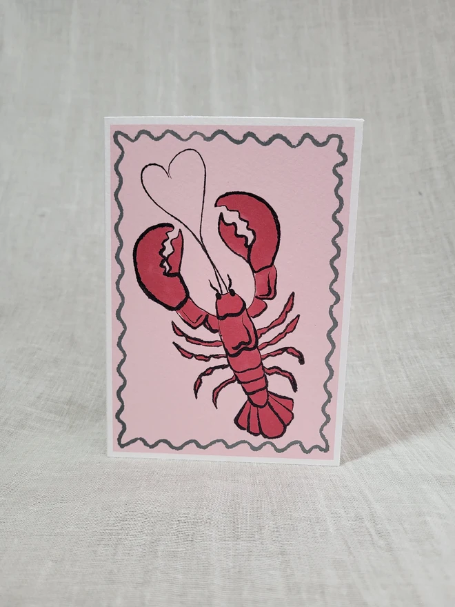 Pale pink greetings card with red lobster design