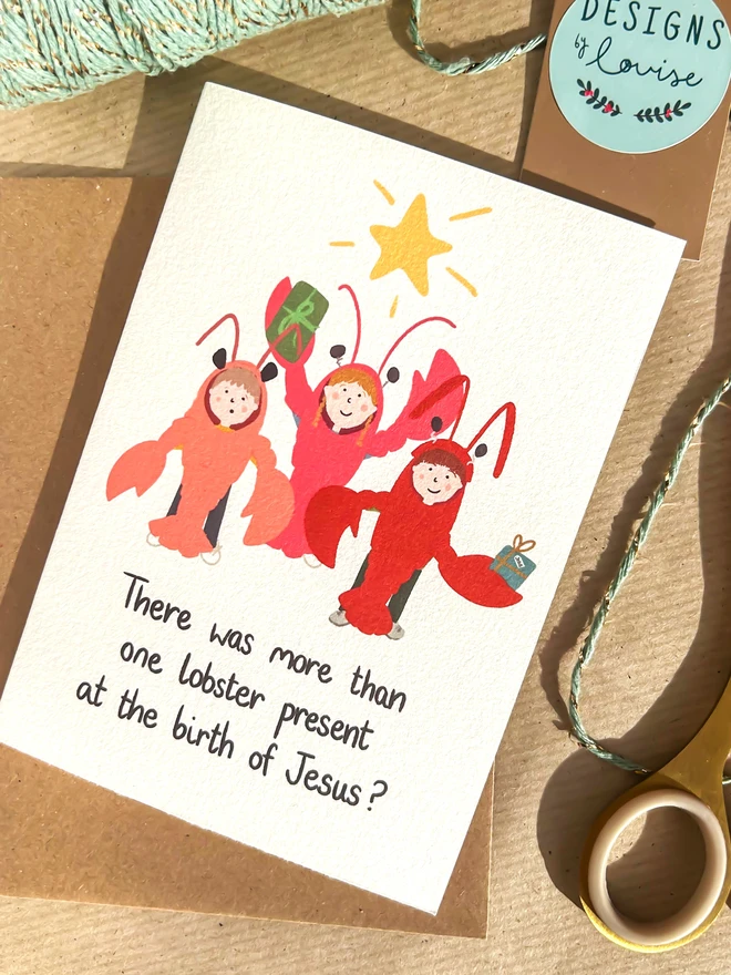 Illustration of a group of children dressed in lobster costumes holding Christmas gifts and standing under a yellow star. Quote below reads 'There was more than one lobster present at the birth of Jesus?'