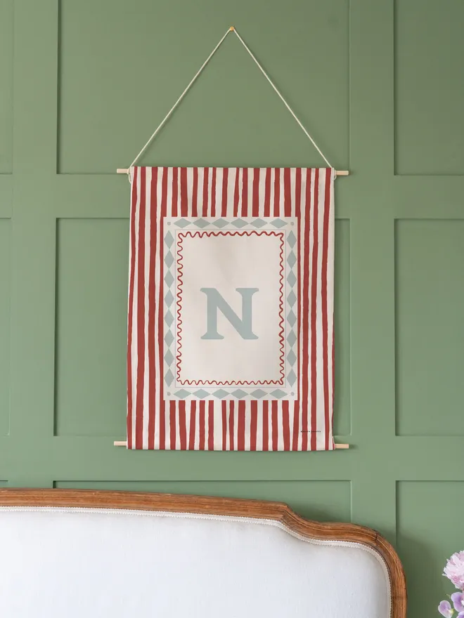 Stripe Initial Fabric Banner, hanging on a green wall. 