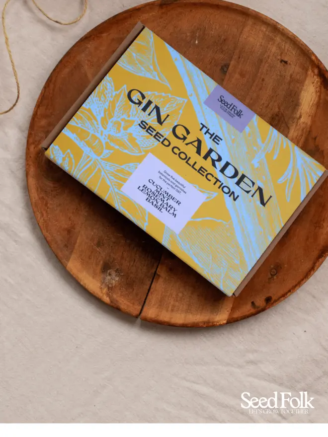 The Gin Garden Seed Collection Box. Beautiful box illustrated in blue and yellow botanical print, photographed on a wooden tray. 