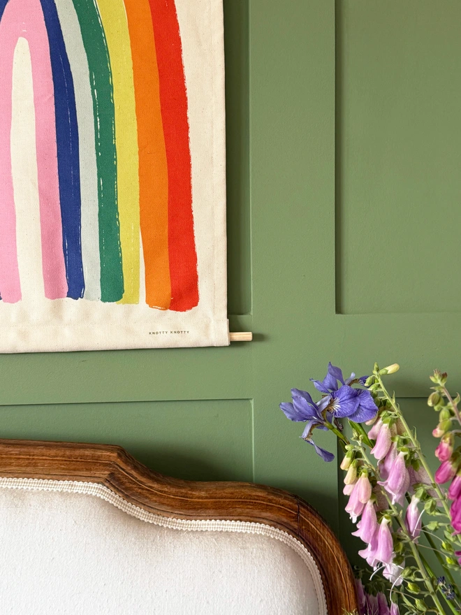 Cotton Bright Rainbow Fabric Banner, against a green wall. 