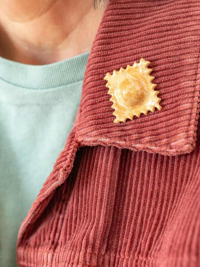ceramic pasta pin badges. a ceramic raviolini badge photographed on a jacket.