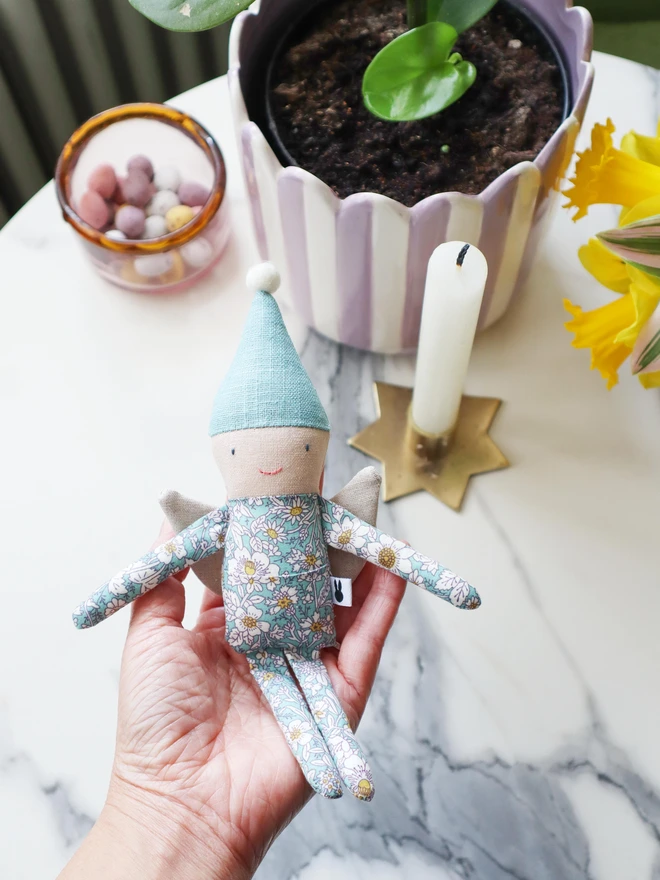 handmade fairy doll in light blue floral outfit and light blue pointy hat with cream pompom on top. 