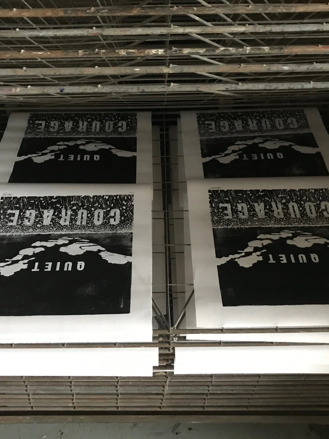 four 'Quiet Courage' letterpress prints drying on a drying rack