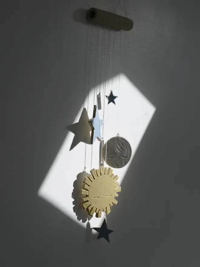 sun moon and stars hanging in beam of light on dark wall