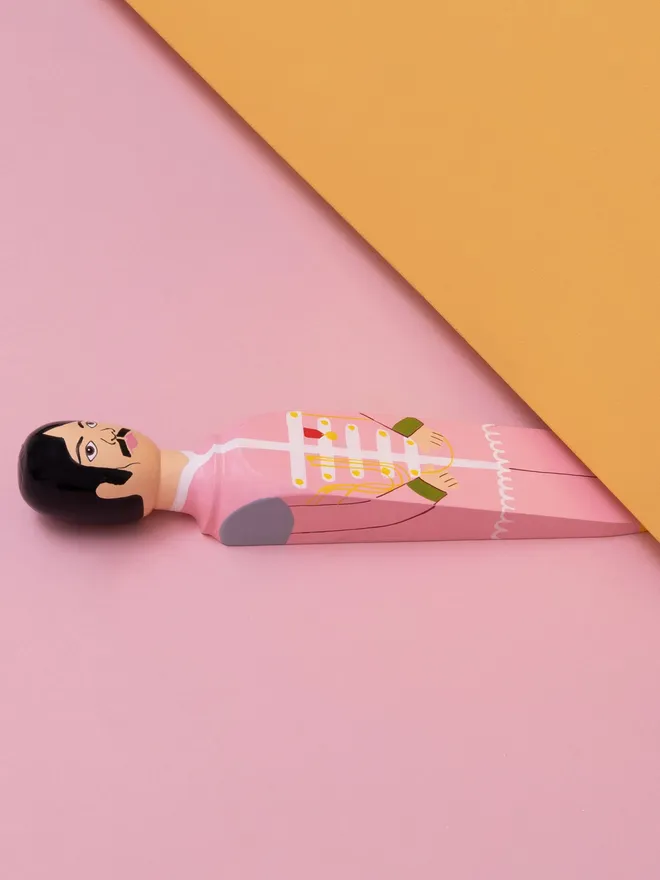 Wooden Door Stopper (Georgy), a colourful wooden door stop sitting under a door.