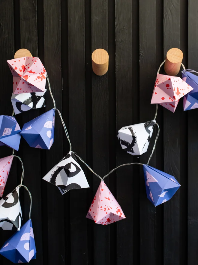 sting of origami fairy lights strung up on wooden hooks
