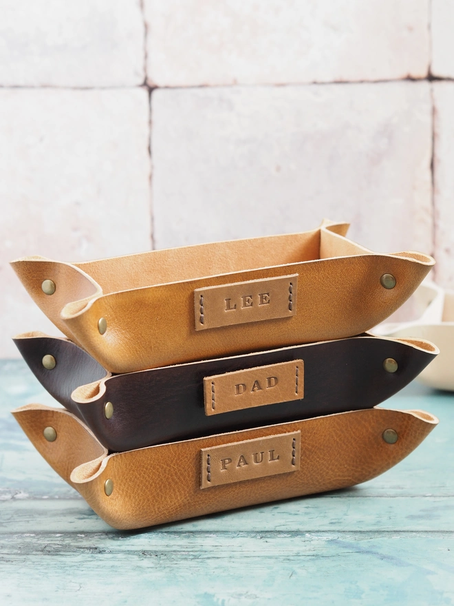 Personalised leather trays. A stack of 3 leather trays sit on top of each other, a mix of hand dyed tan and dark brown colours.