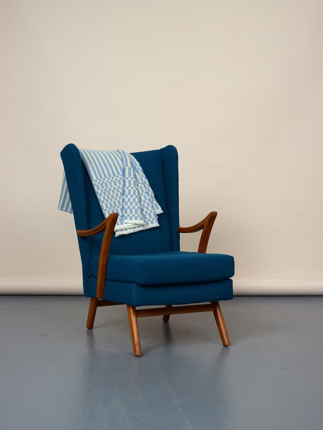 cham lambswool blanket. a blue and yellow striped blanket photographed thrown over a blue chair. 