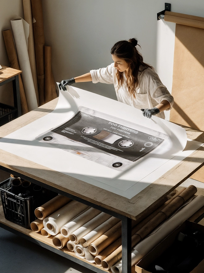 foo fighters cassette tape print. artist unrolling print on studio desk.