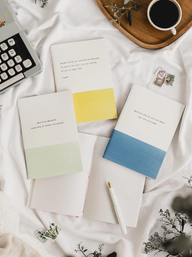 handmade eco-friendly, personalised notebooks with text typed on the cover in pale green, yellow, blue and white