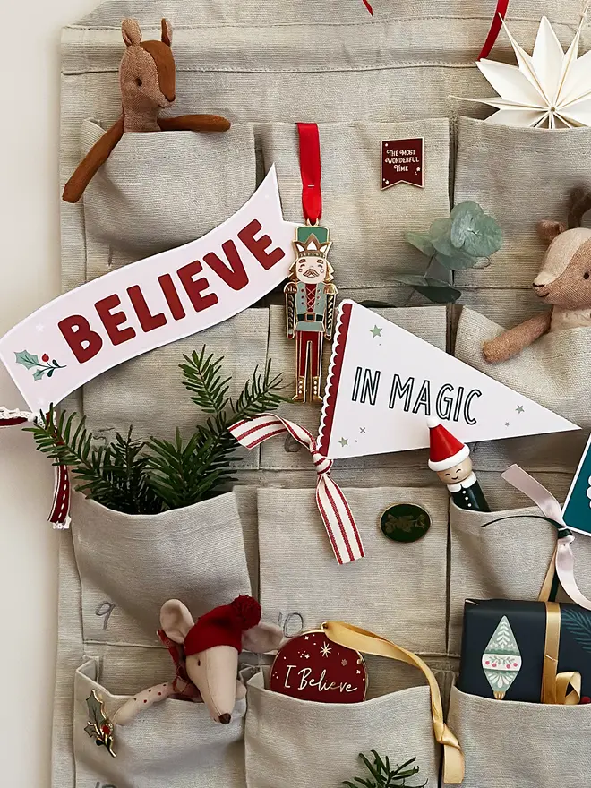 Believe in magic Christmas flags are tucked into a fabric advent calendar along with various trinkets and gifts.