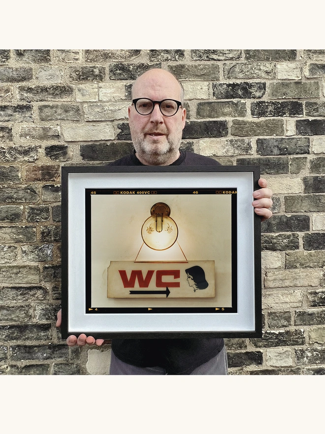 Richard Heeps holding WC sign photograph small framed in black