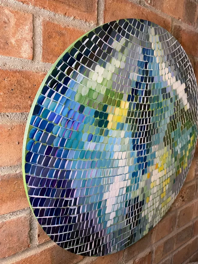 a side view of a round green and blue painting on a brick wall