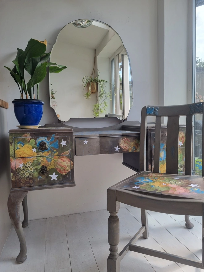Vintage painted dressing table and chair. Painted in coffee grey and decorated using layered antique florals with yellow and blue accents and finished with hand-cut white paper stars. Text reads in blue 'think happy thoughts'. Heavily distressed finish.