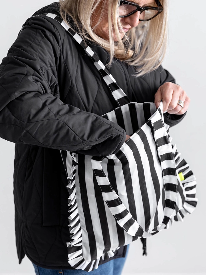 Lady with black jacket with black and white tripped cotton frill tote bag on her shoulder