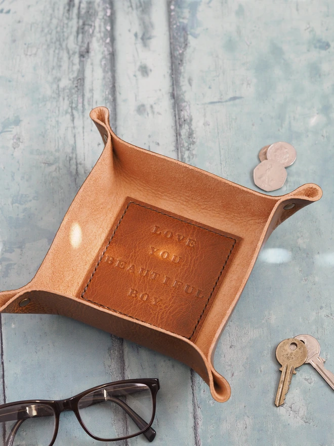 Personalised message leather coin tray. Hand dyed tan brown leather tray with a square stitched to the base which is personalised with a short but sweet message.