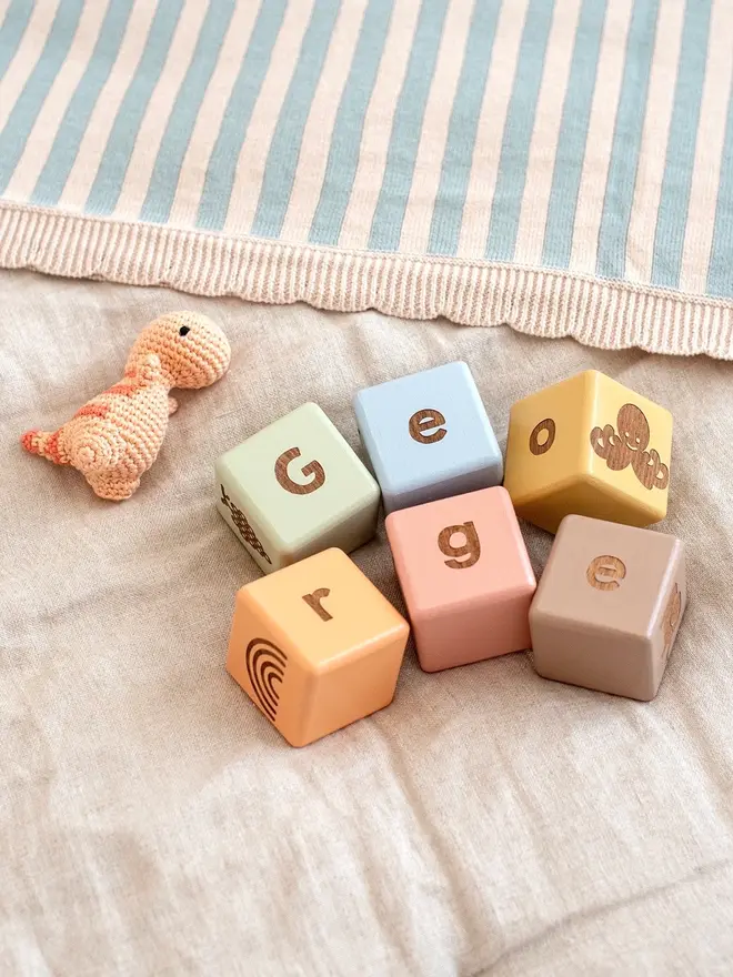 wooden baby letter blocks. a selection of square wooden blocks with engraved letters and illustrations, in various colours. 