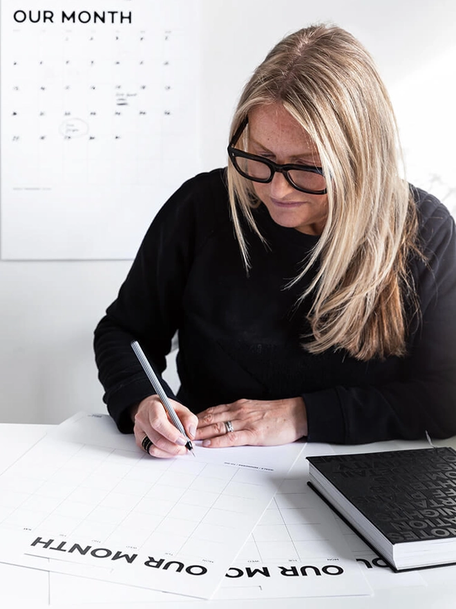 Female at desk filling in her. yearly wall planner
