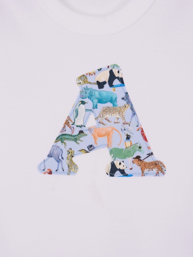 A close up of a bodysuit with an initial on the front cut from Liberty zoo animal print