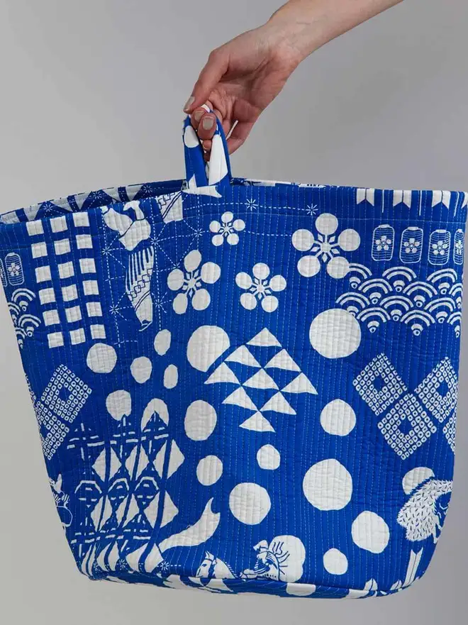 Blue Festival Quilted Storage Basket, a person holding a blue basket against a grey backdrop. 
