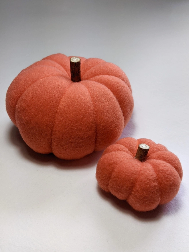 A big and small plump orange fleece pumpkin decorations on a white background
