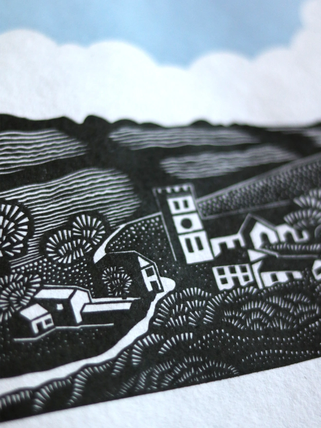 Original handmade linocut print featuring a Cornish village with a church, houses, fields and trees
