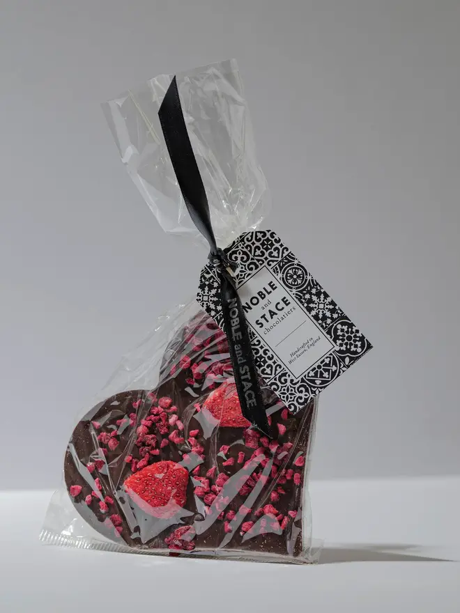 Dark chocolate & red berry heart wrapped in clear plastic and with a green tag. 