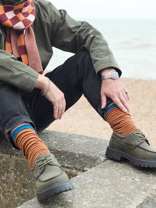 man by the sea wearing red and mustard striped socks