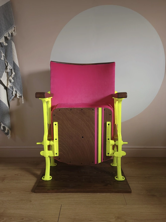 Hot pink velvet vintage cinema seat with neon painted details under the seat up 