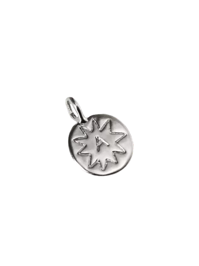 a silver frisbee pendant, shaped like a coin with a hand engraved 'A' inside a star doodle.