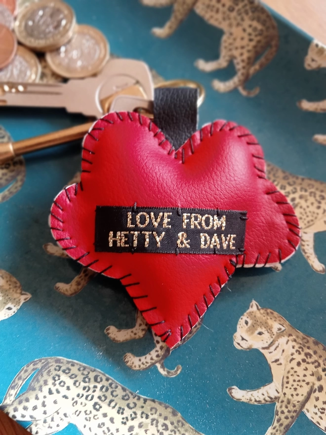 The red leatherette reverse of a heart keyring, showing the black label with LOVE FROM HETTY & DAVE in gold lettering