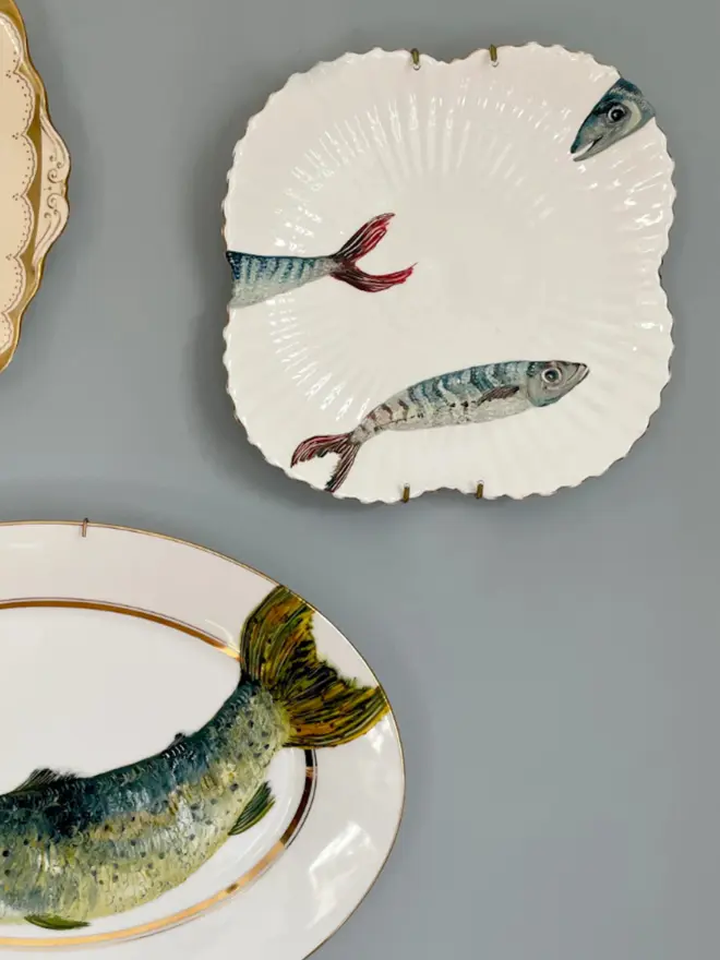 Plate-scape. Fine Art Oil Painted Three mackerels On A vintage Plate, hanging on a white wall.