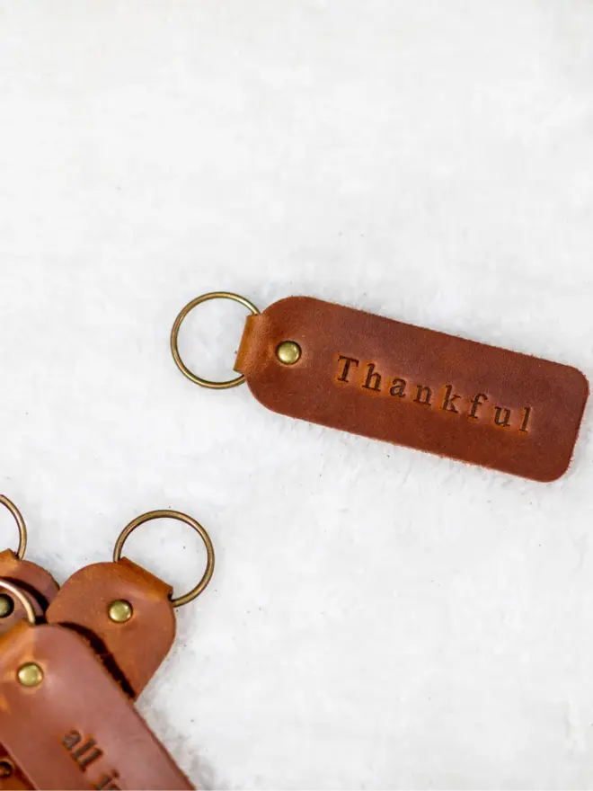 custom leather embossed keyring. a light brown leather keyring embossed with 'thankful' photographed against a white background.