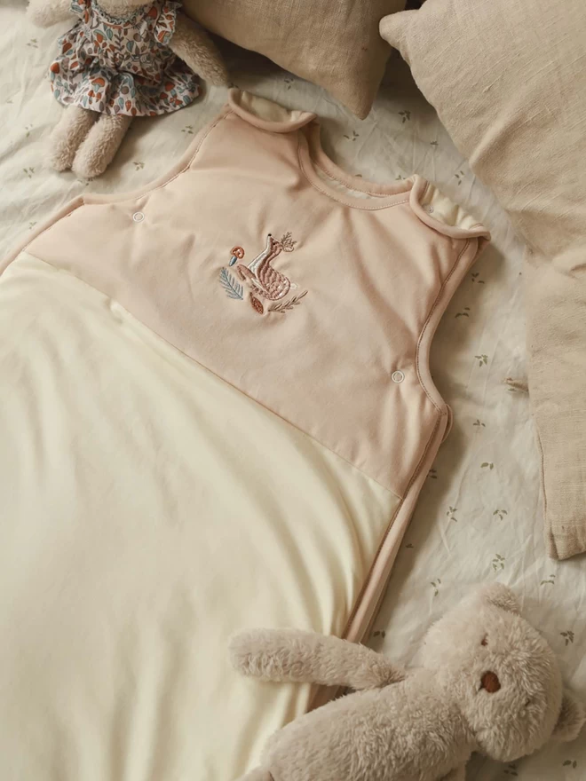 Baby sleeping bag lying on a bed with teddy bears