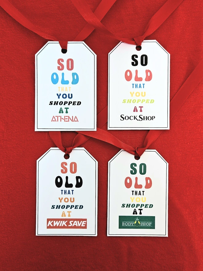 Four gift tags that say so old you shopped at Athena, Sock Shop, Kwik Save and Body Shop written in brightly coloured fonts with a red ribbon