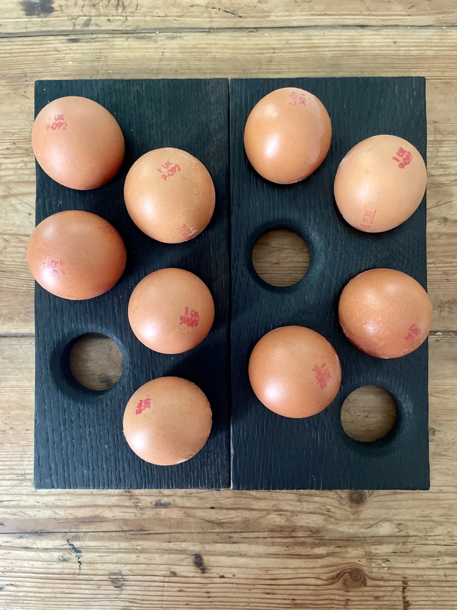 Two egg holders charred black Yakisugi with five brown eggs randomly placed