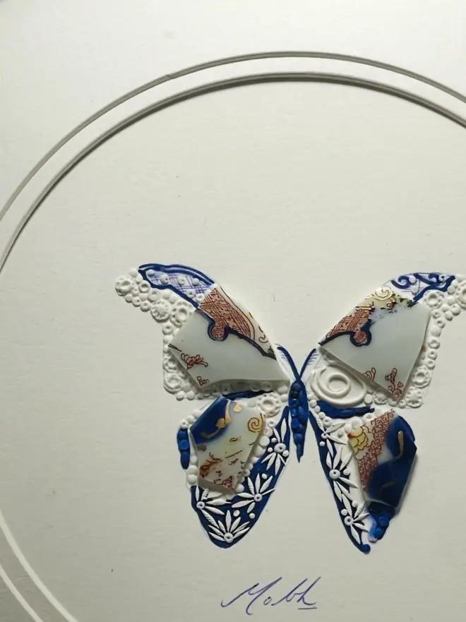 Hand-drawn, painted, mosaic clay, vintage Japanese pottery insect on white double mounted card, in a black circular frame.