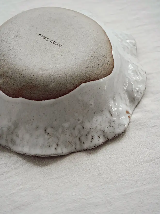 Dapple Stoneware Cereal & Salad Bowl, the flip side of the bowl, placed on a table cloth. 