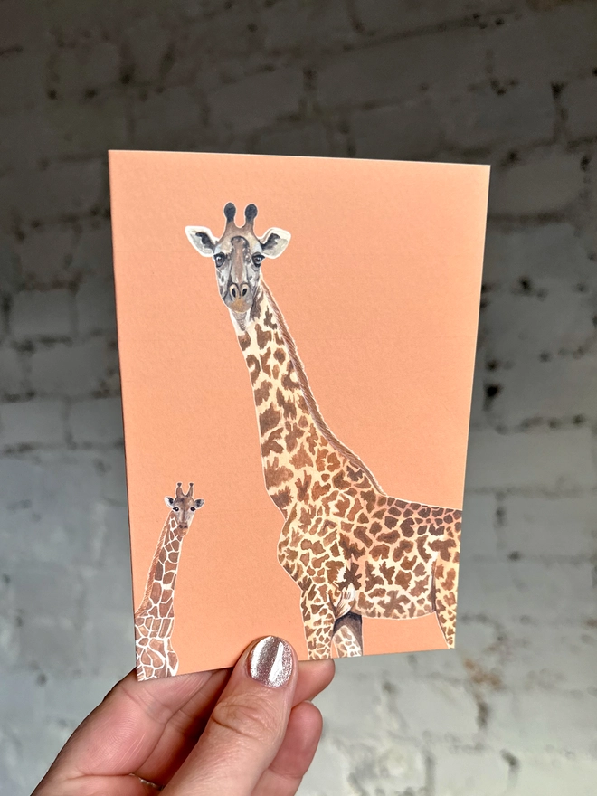an orange greetings card featuring illustrations of two giraffes