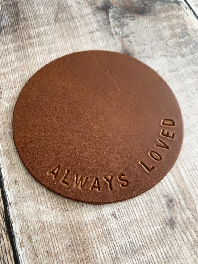 Tan leather coaster stamped with 'always loved'