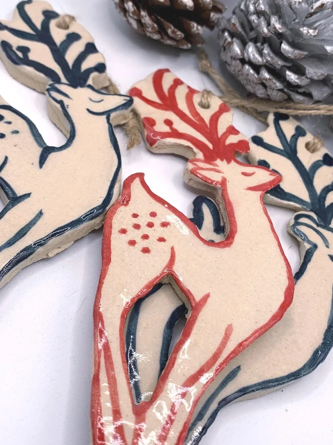 Handmade Ceramic Reindeer Ornament Scandinavian Folk Decor, a group of colourful reindeer decorations sitting on a plain white surface. 