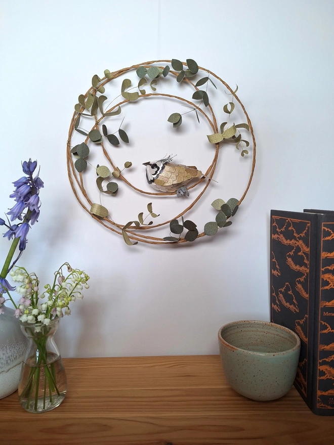 Handmade paper sculpture of a crested tit bird perched on a leafy wreath. Original wall art by Kaper