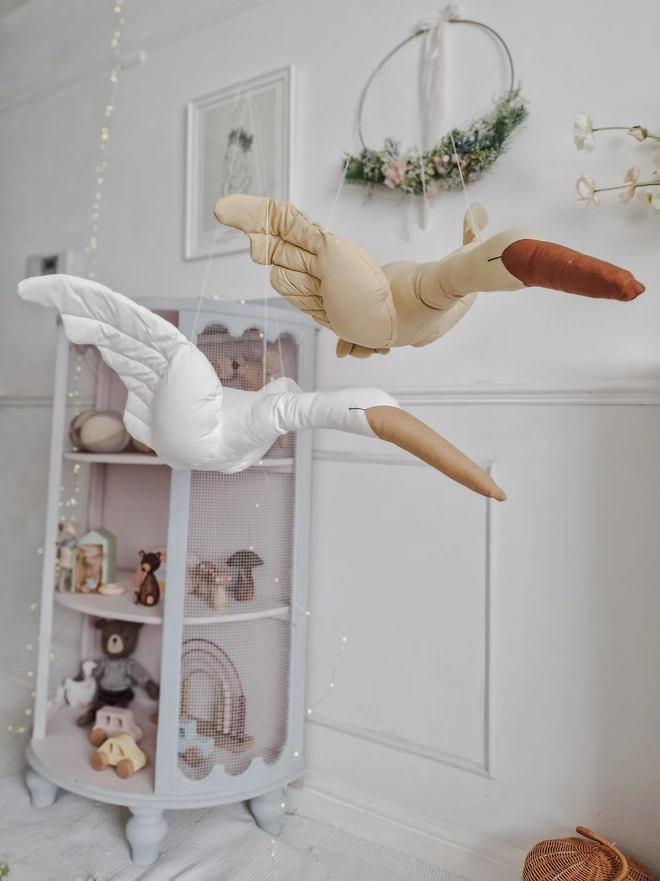 Flying Swan Hanging Decoration, a hanging beige swan decoration, suspended in a child's bedroom. 