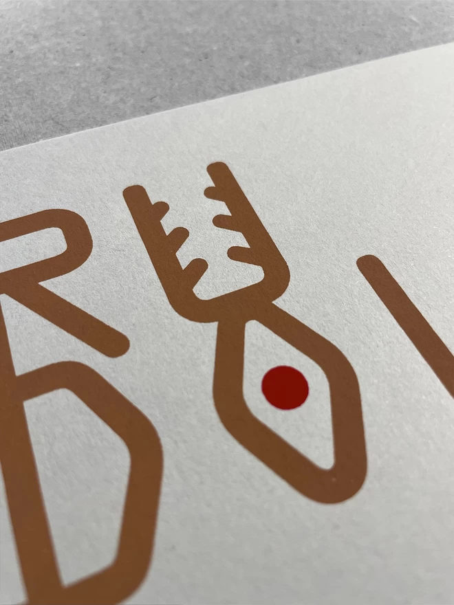 Close up of the screenprinted lettering that spells Rudolf but also looks like a reindeer. The U and the O stack to depict a reindeer.